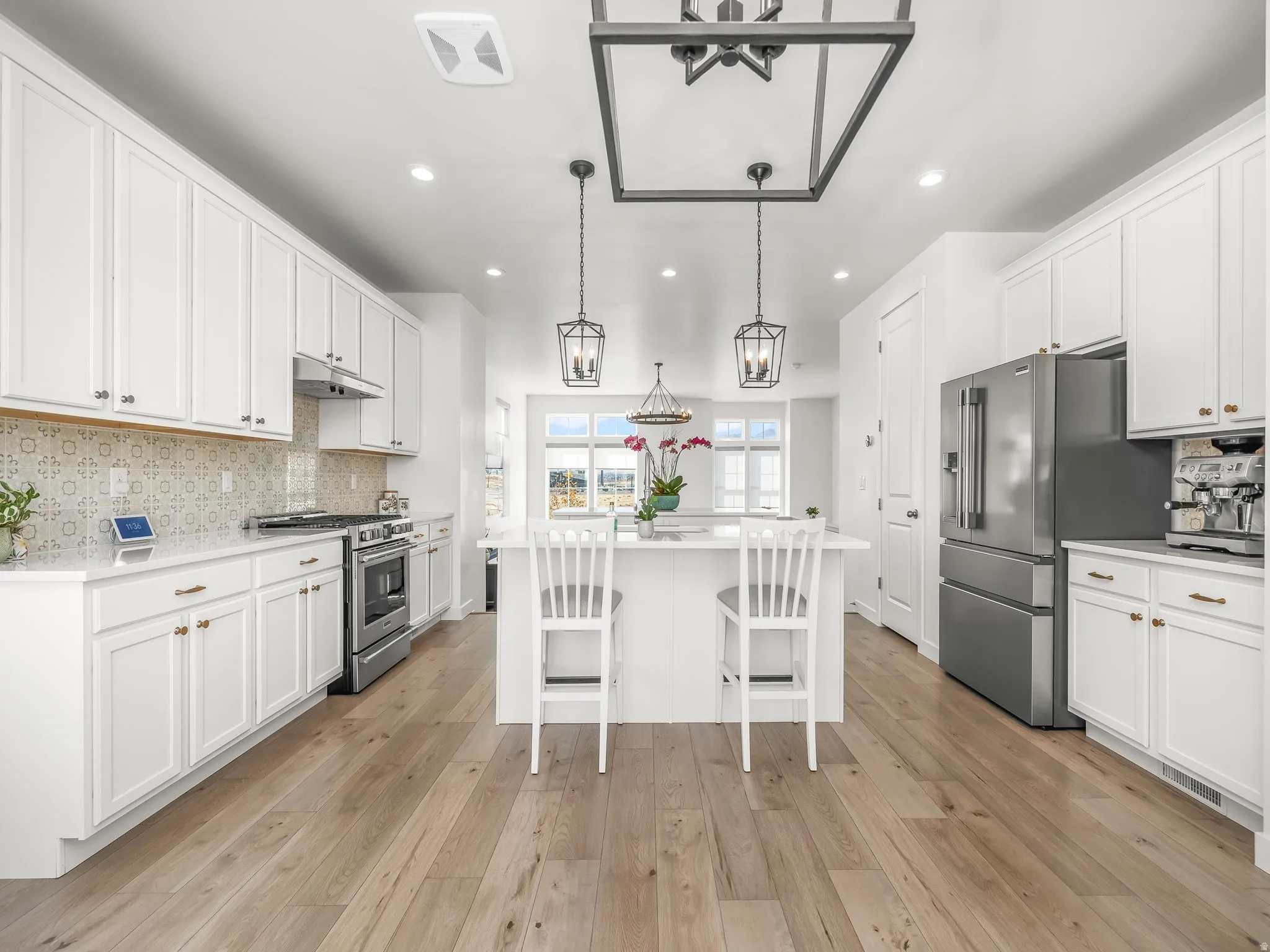 Kitchen featuring tasteful backsplash, appliances with stainless steel finishes, white cabinets, a center island, and recessed lighting