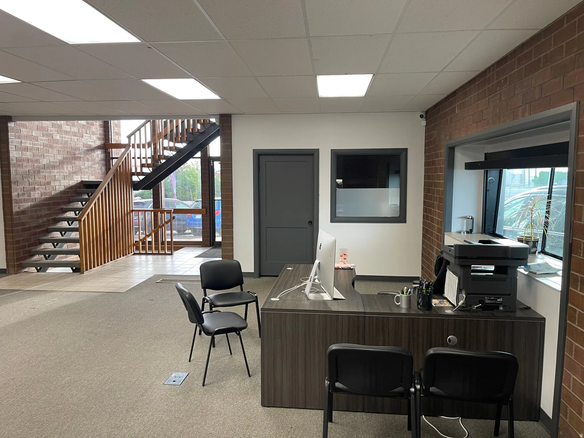 Office with brick wall and a paneled ceiling