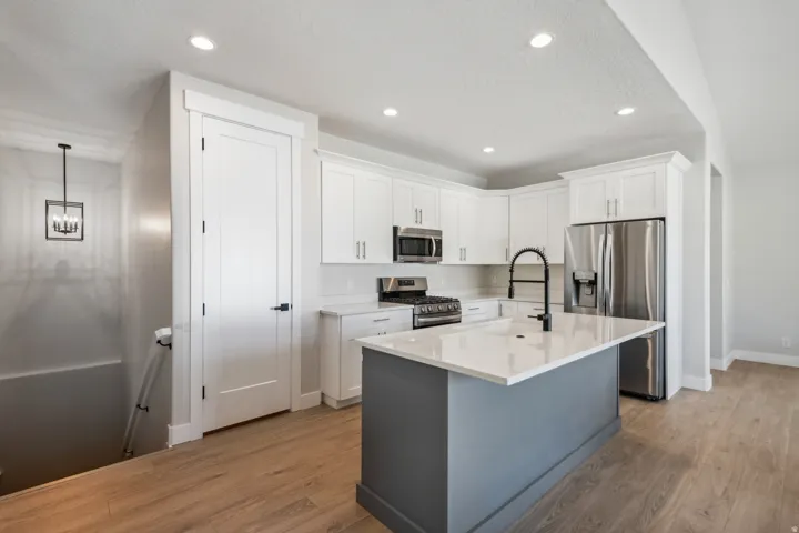 Kitchen with appliances with stainless steel finishes, white cabinets, light wood finished floors, a center island with sink, and recessed lighting