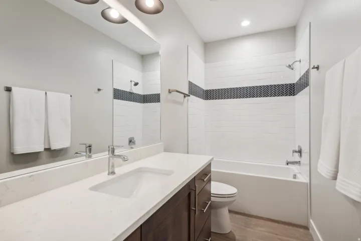 Bathroom featuring light wood finished floors, vanity, and shower / tub combination