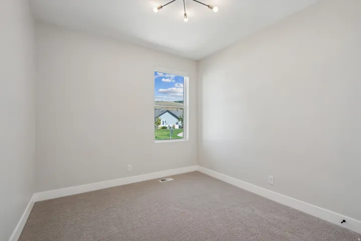 Carpeted empty room with baseboards and a chandelier