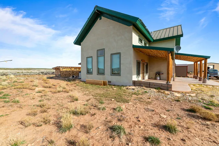 Rear view of house featuring stucco siding, a patio area, a metal roof, and a standing seam roof