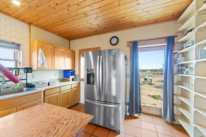 Kitchen featuring stainless steel fridge with ice dispenser, light countertops, healthy amount of natural light, light tile patterned flooring, and wood ceiling