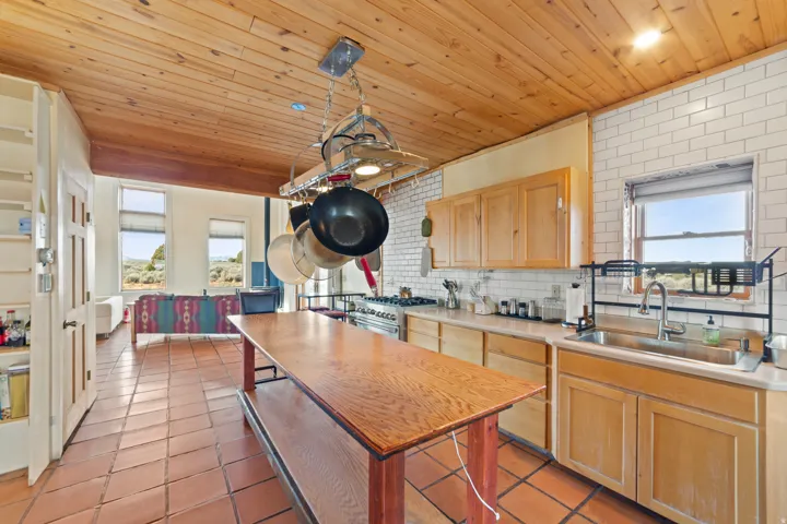 Kitchen featuring light brown cabinetry, light countertops, light tile patterned floors, backsplash, and wood ceiling