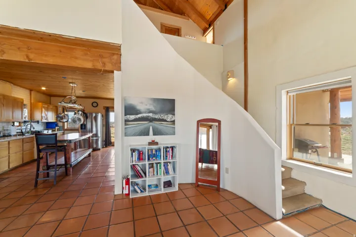 Interior space with a wooden ceiling with exposed beams, tile patterned floors, a high ceiling, and arched walkways