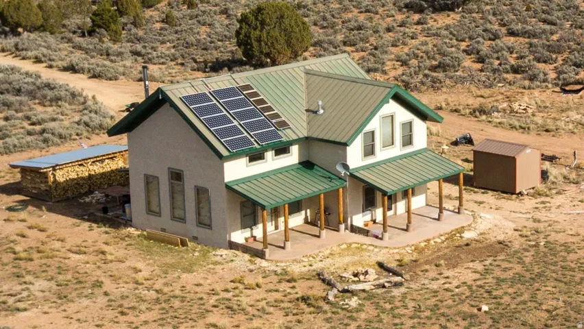 Back of property featuring solar panels, a porch, a standing seam roof, and view of desert
