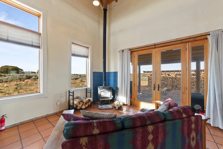 Living room featuring tile patterned flooring, a wood stove, a high ceiling, and french doors