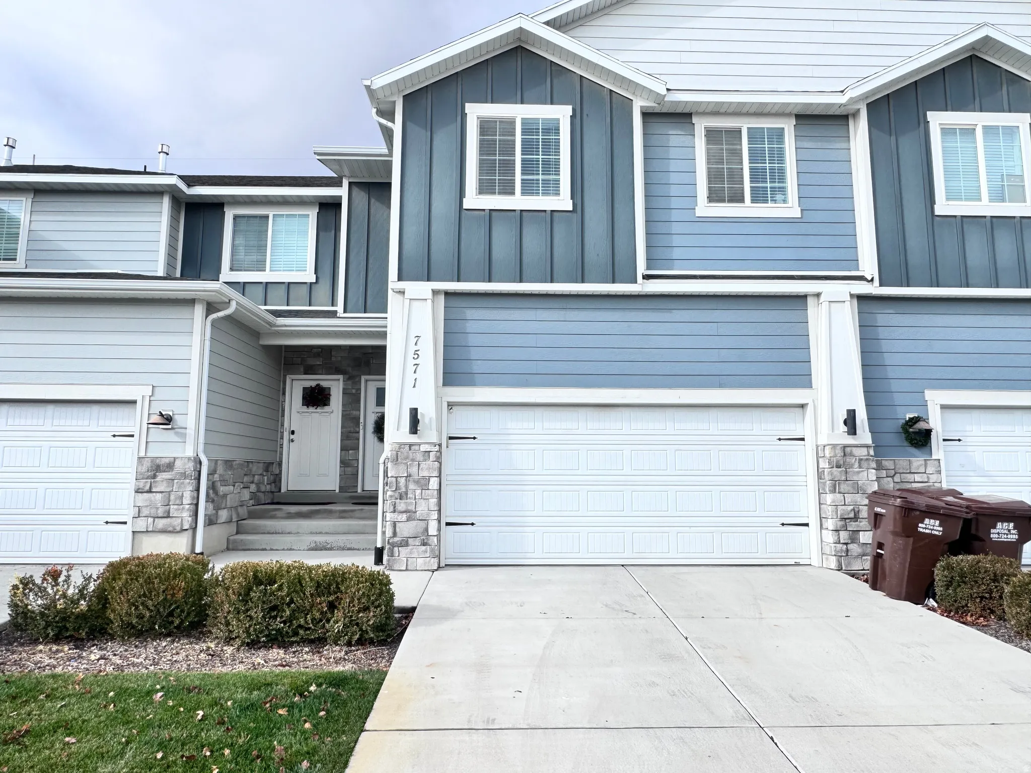 Craftsman-style house with board and batten siding, stone siding, driveway, and an attached garage