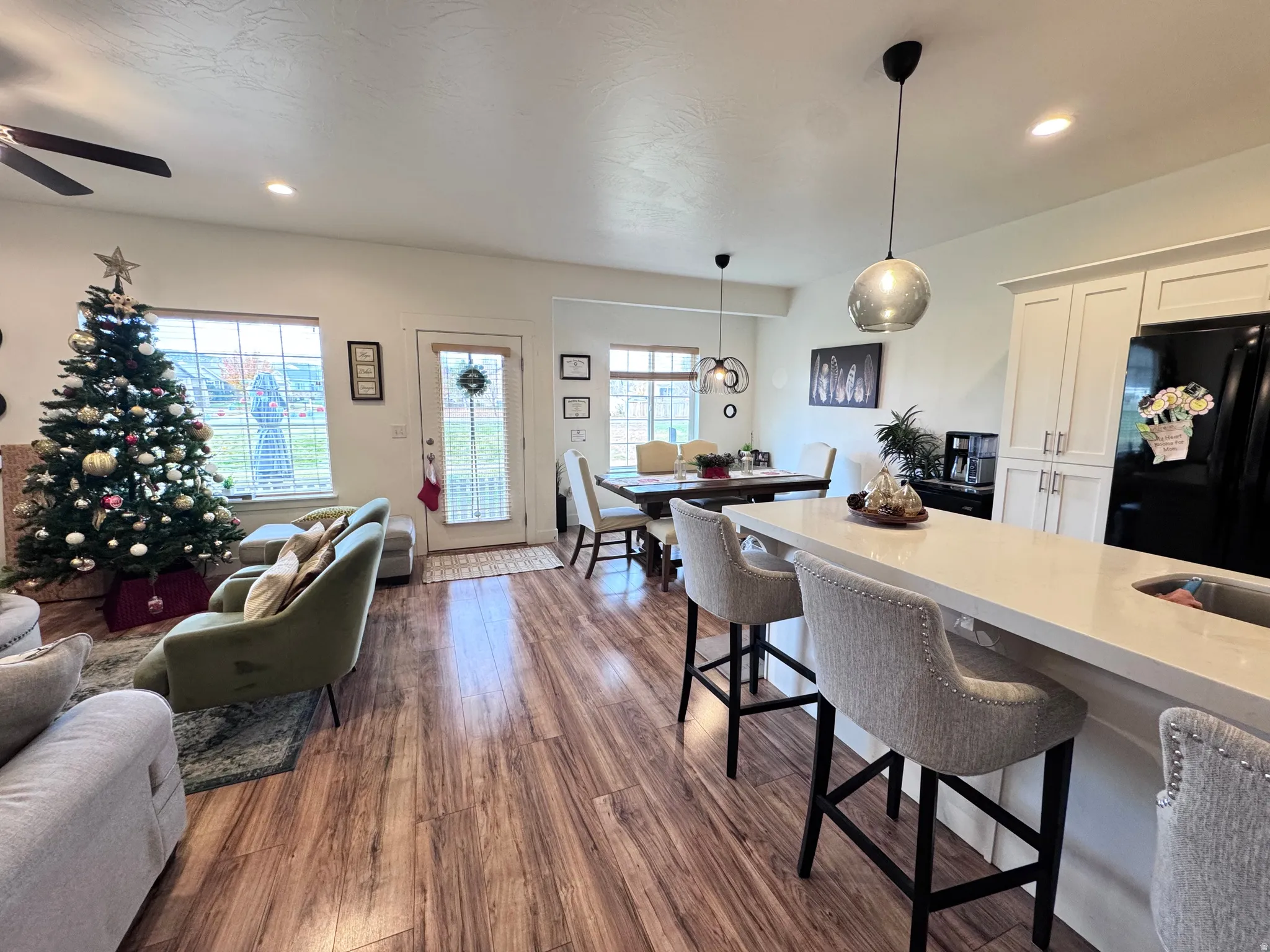 Kitchen featuring a kitchen bar, open floor plan, recessed lighting, freestanding refrigerator, and dark wood-style flooring
