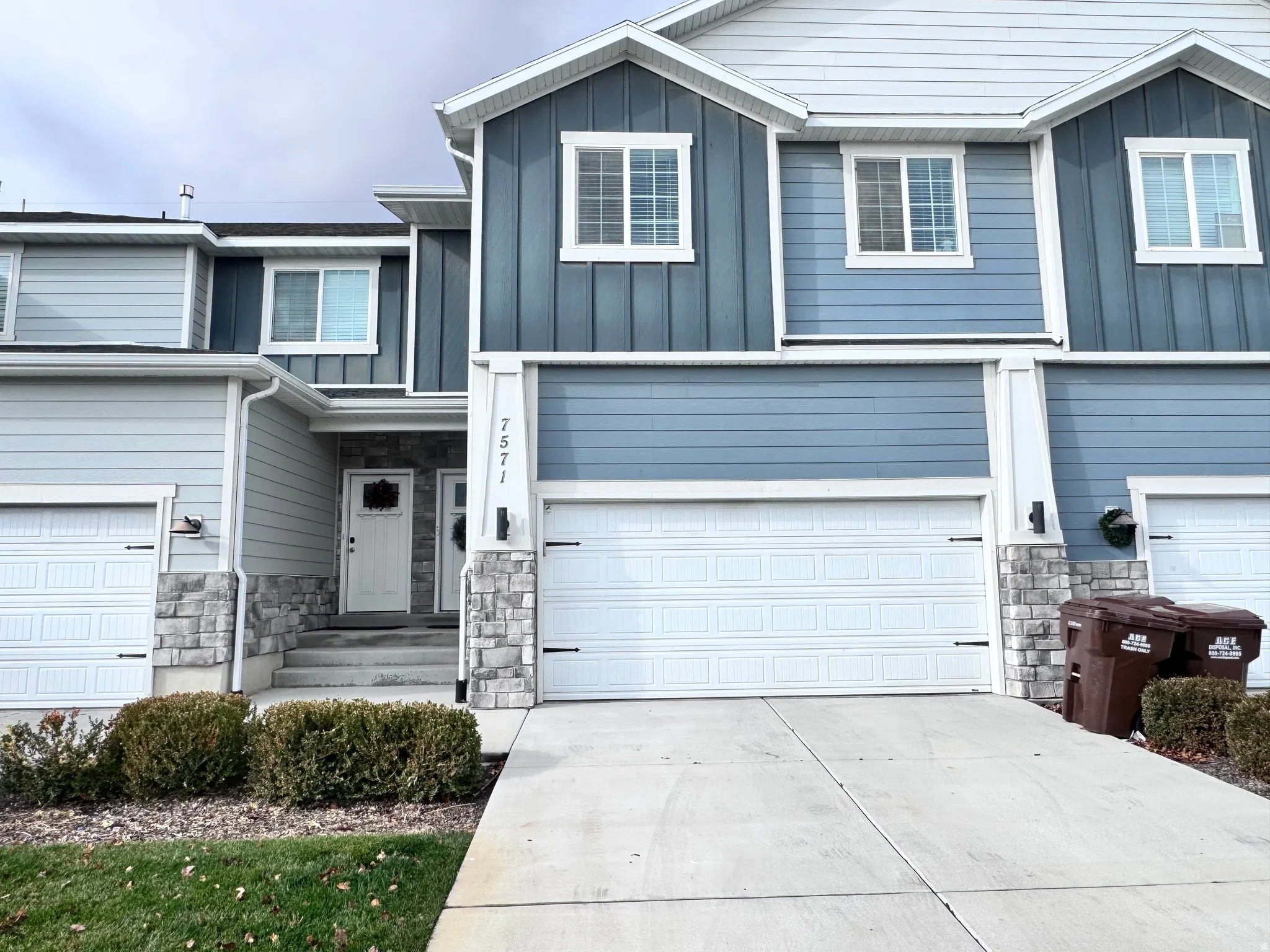 Craftsman inspired home with board and batten siding, stone siding, concrete driveway, and an attached garage