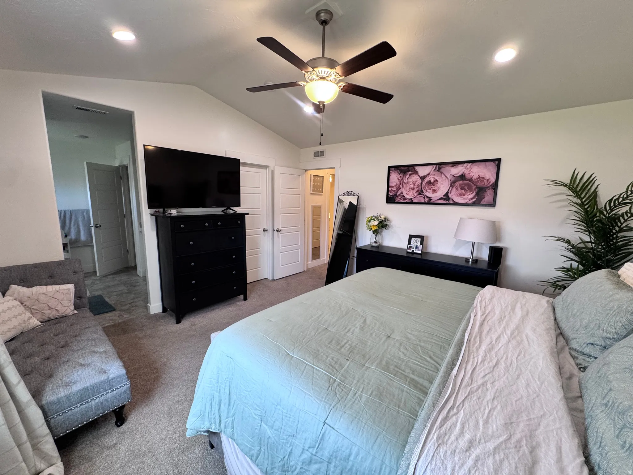 Bedroom featuring vaulted ceiling, carpet flooring, and a ceiling fan
