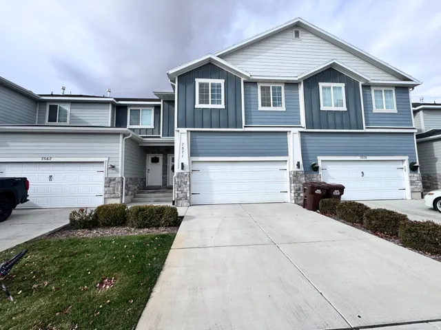 View of front of house featuring stone siding, board and batten siding, and driveway