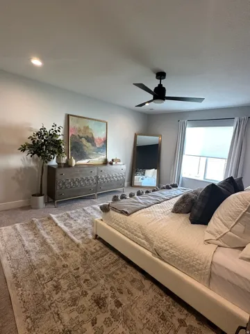 Carpeted bedroom featuring ceiling fan and baseboards