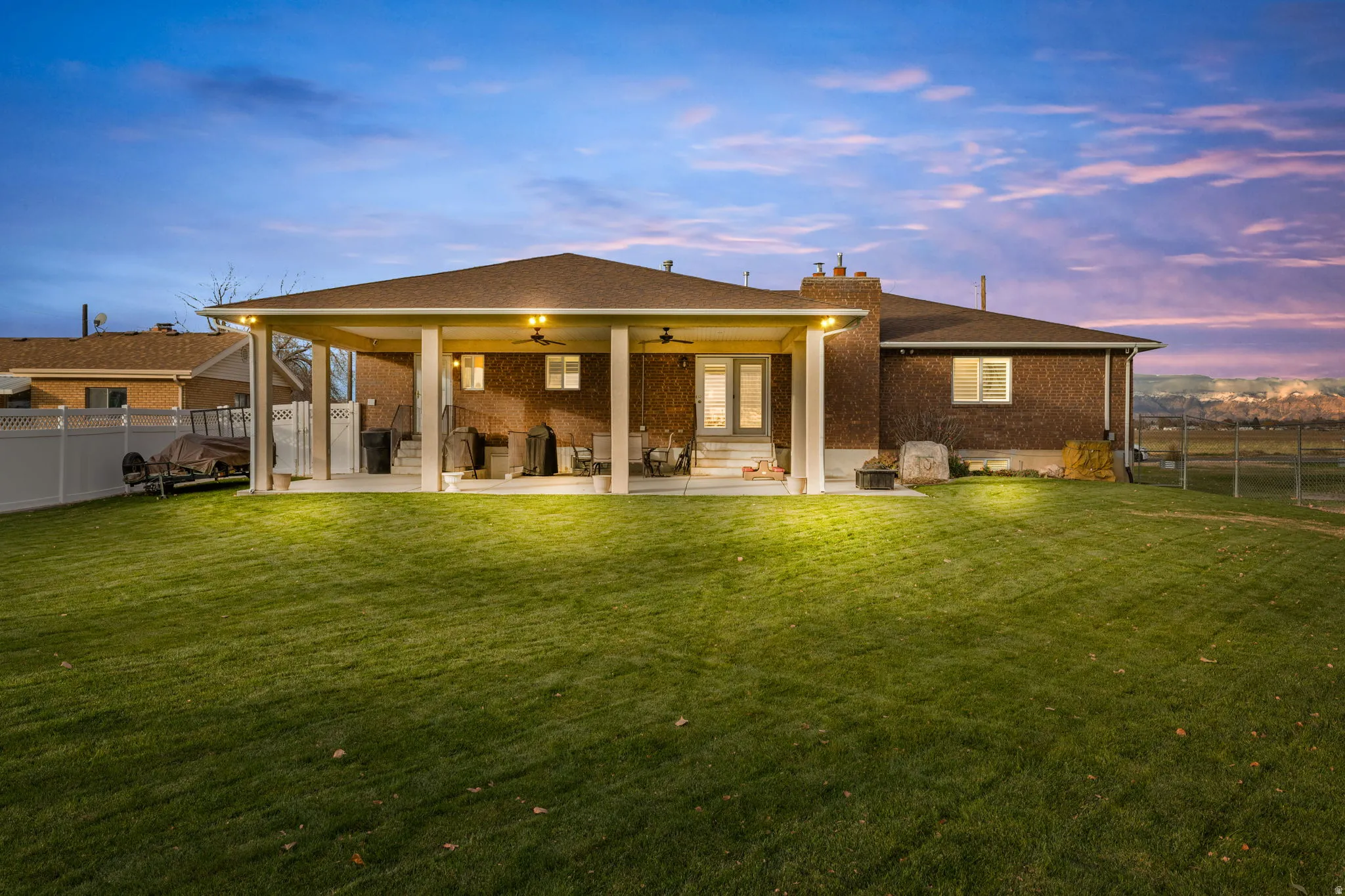 Back of property with a fenced backyard, a patio area, ceiling fan, and brick siding