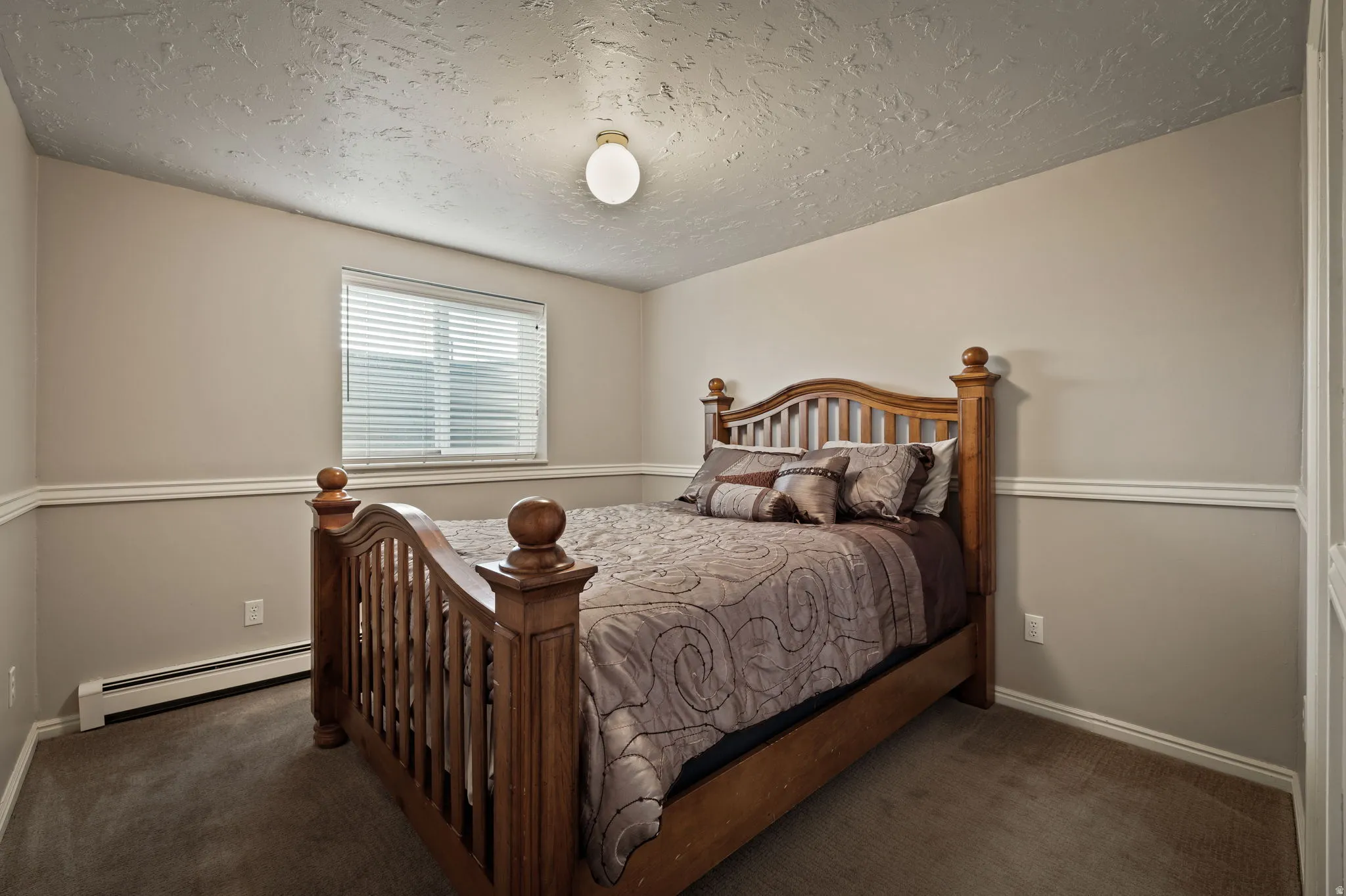 Bedroom featuring a baseboard radiator, dark carpet, and a textured ceiling