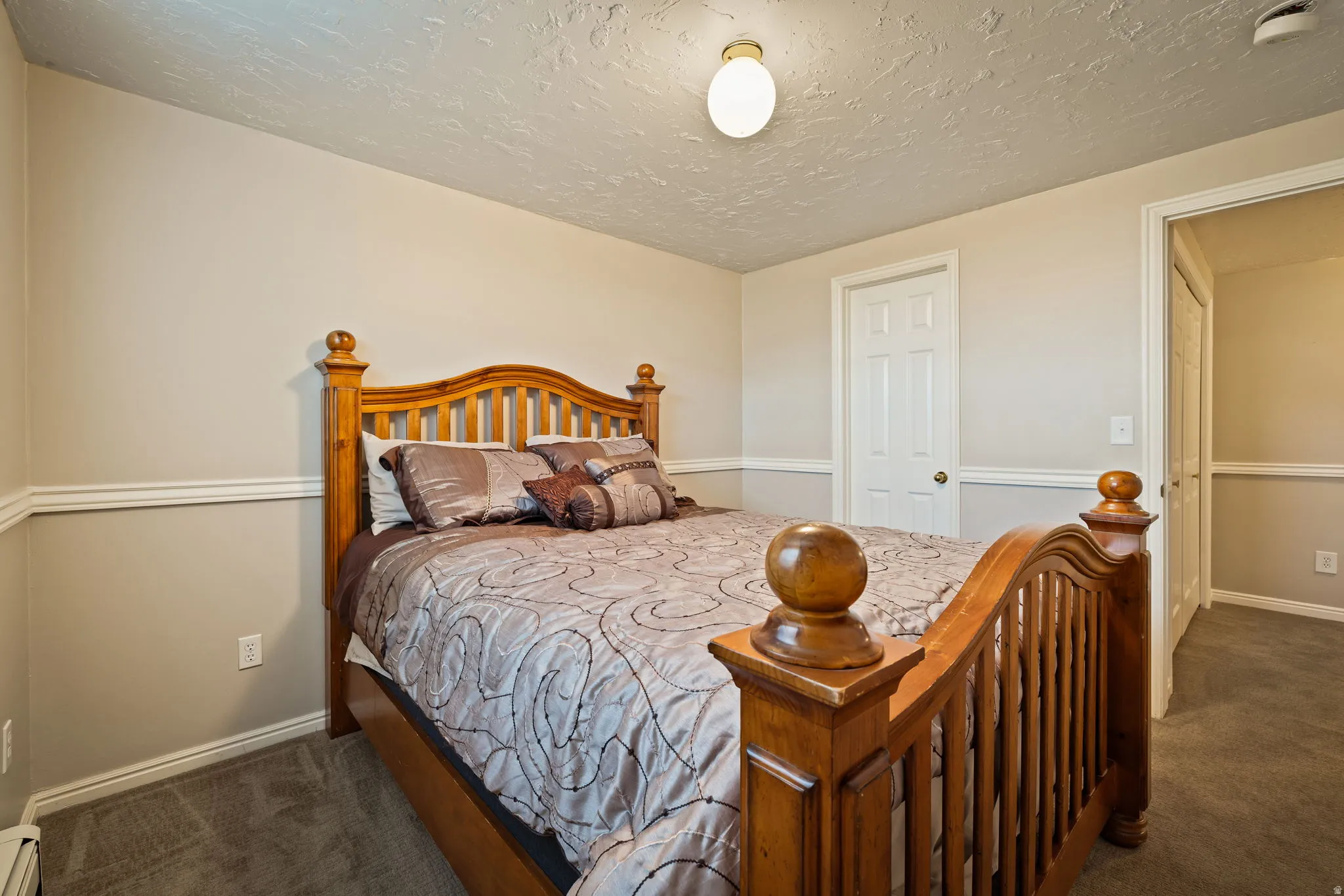 Bedroom with dark colored carpet, a textured ceiling, and a baseboard radiator