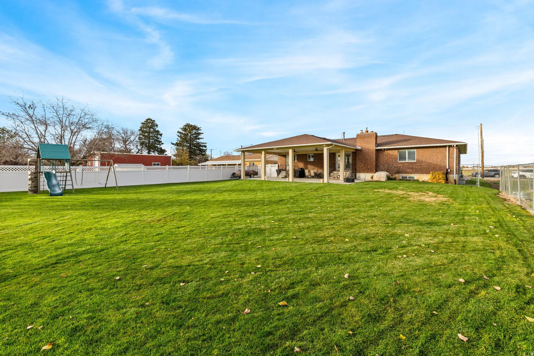 Back of property featuring a fenced backyard, a patio, a chimney, and a playground