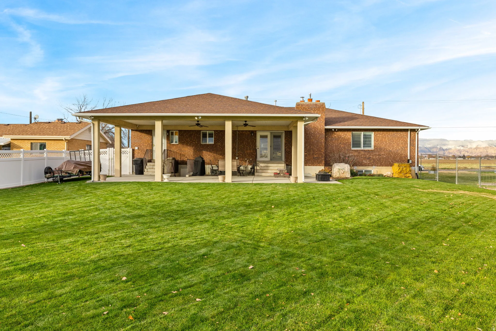 Back of property with a fenced backyard, a patio area, ceiling fan, and brick siding