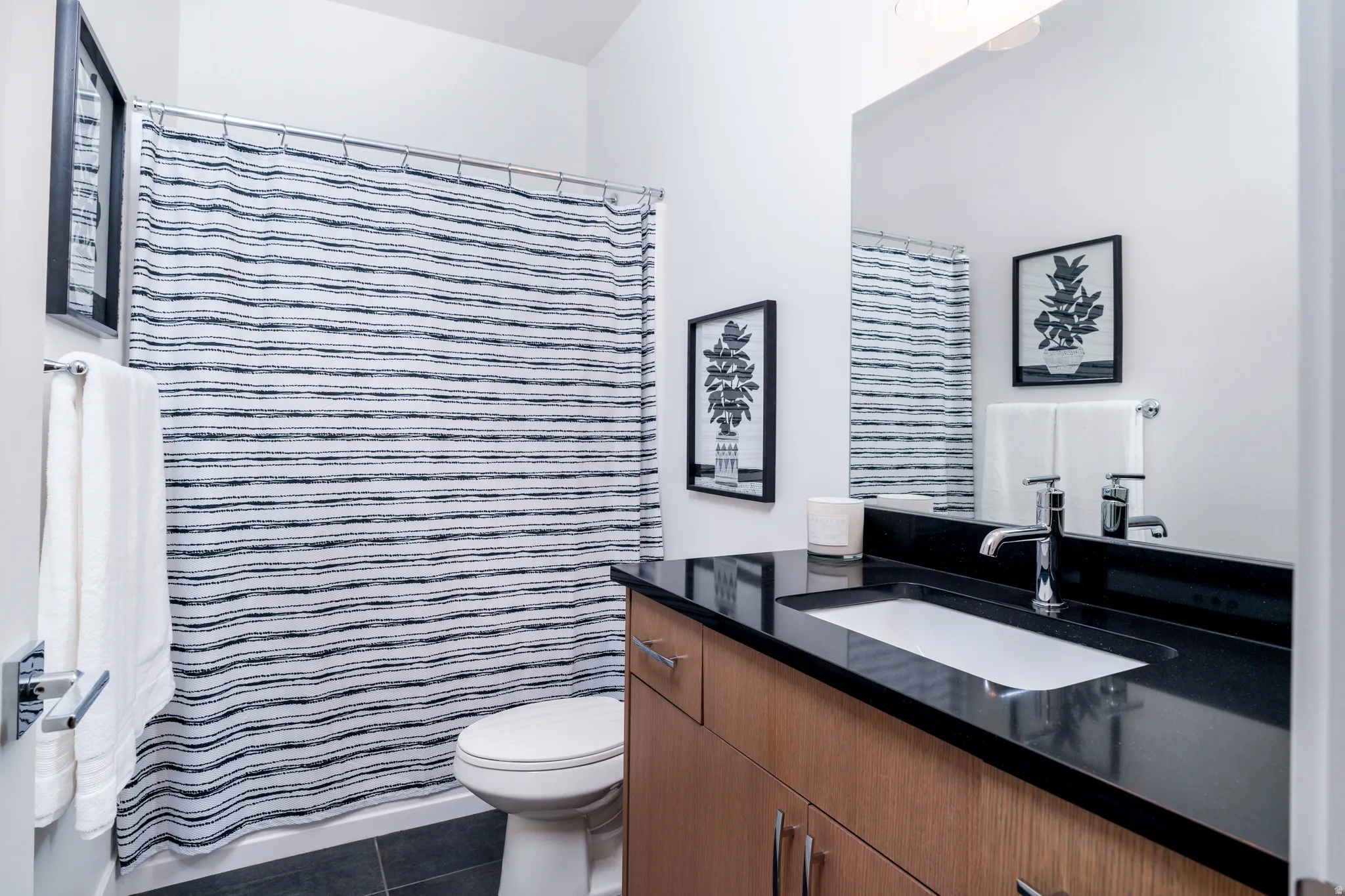 Full bathroom with vanity, dark tile patterned flooring, and a shower with shower curtain