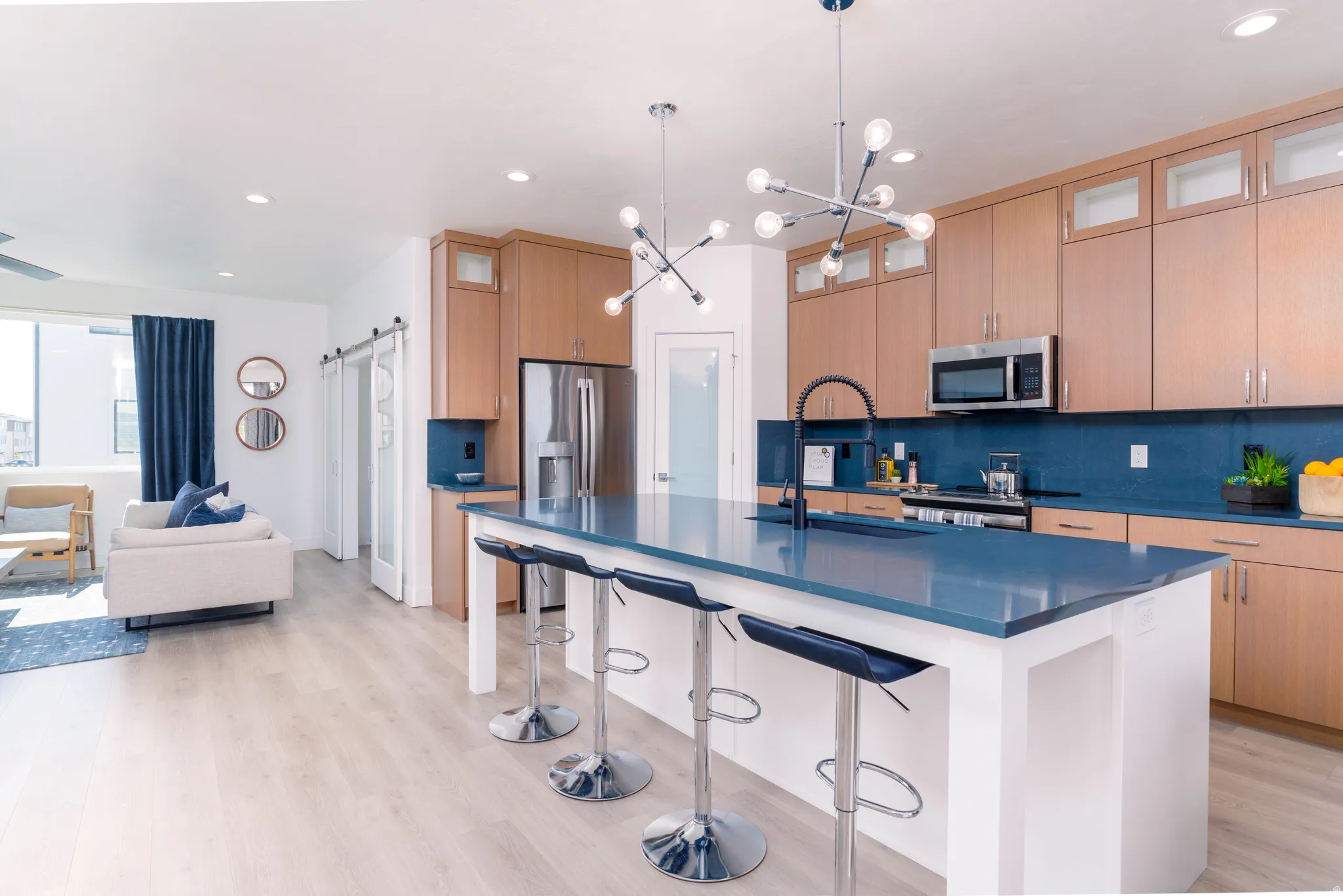 Kitchen featuring a barn door, backsplash, a breakfast bar area, glass insert cabinets, and a kitchen island with sink