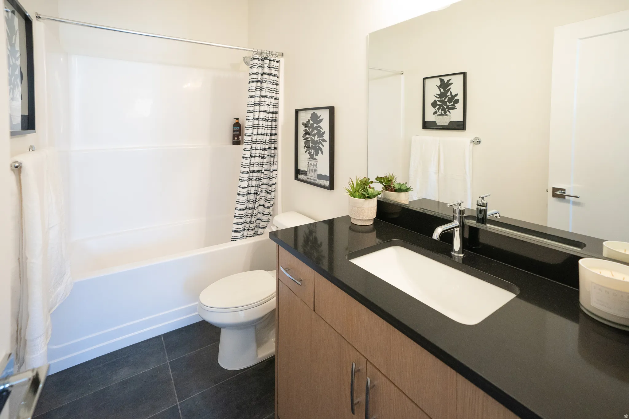 Full bath featuring shower / tub combo, dark tile patterned floors, and vanity