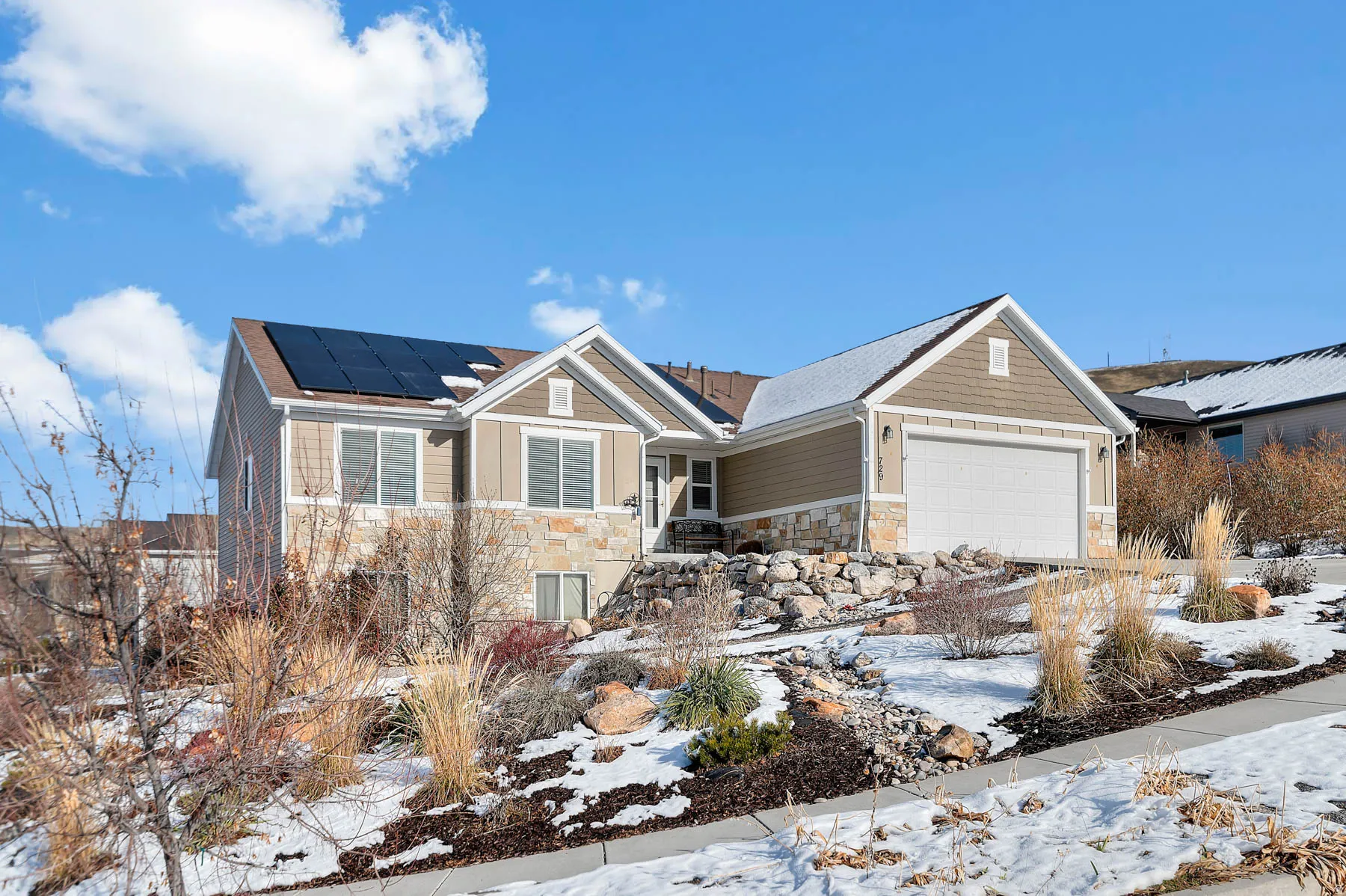 Craftsman inspired home featuring stone siding, solar panels, and an attached garage