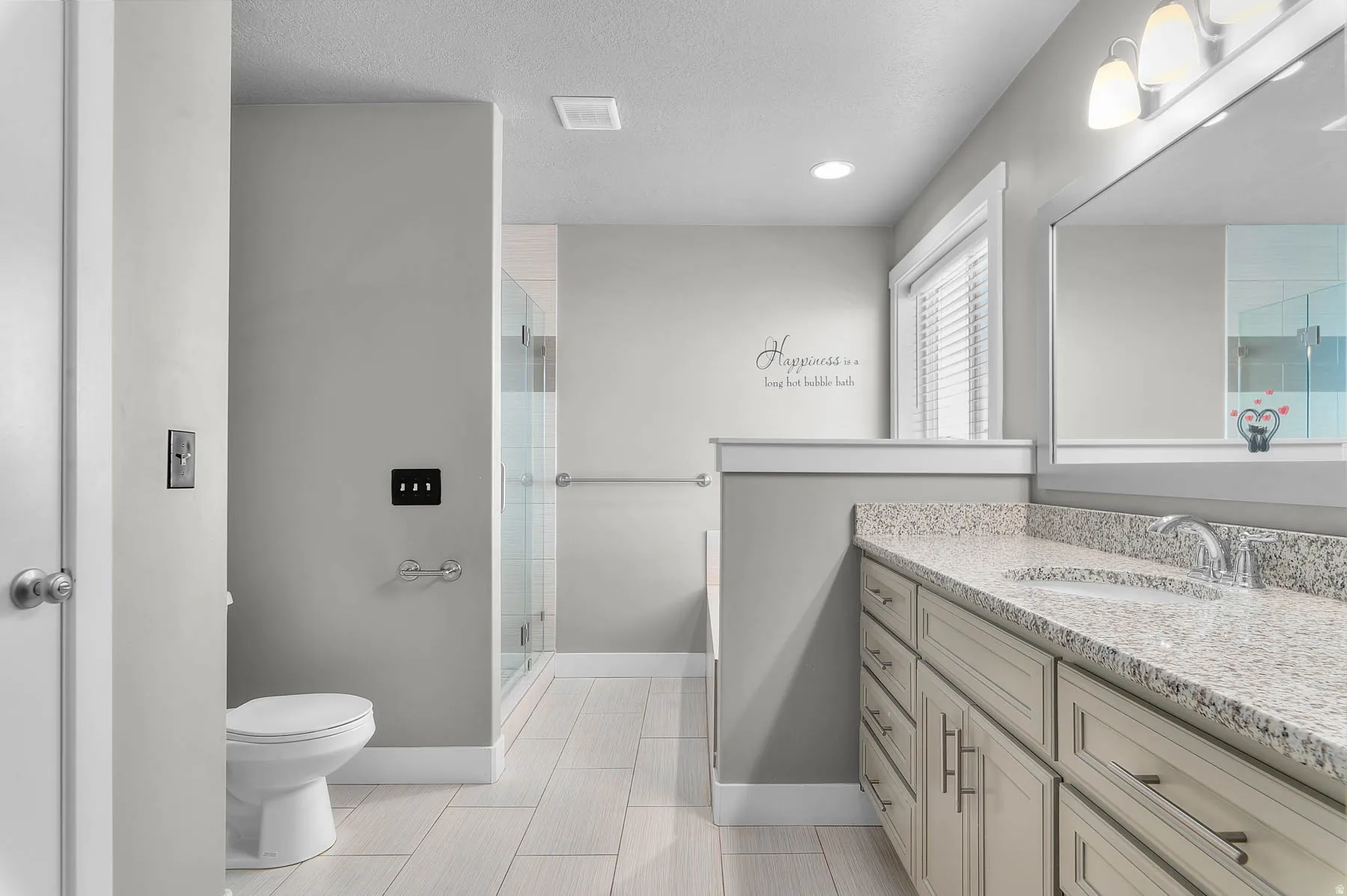 Bathroom with vanity, a shower stall, a textured ceiling, and light tile patterned flooring