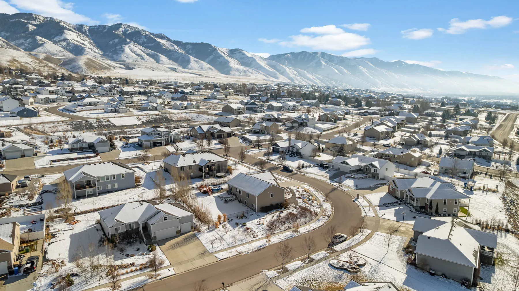 Aerial view of property and surrounding area with a mountain backdrop and nearby suburban area