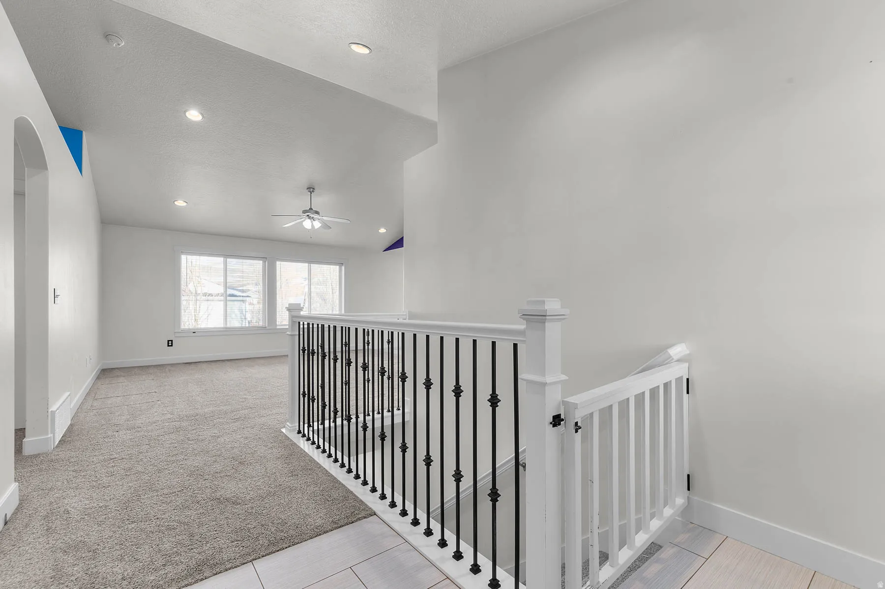 Corridor with vaulted ceiling, an upstairs landing, light colored carpet, arched walkways, and recessed lighting