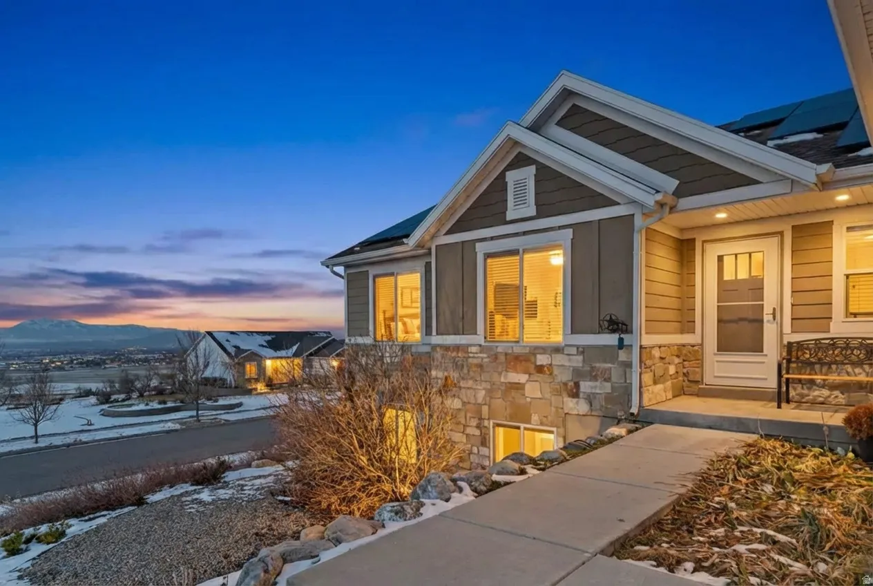 Snow covered property entrance with roof mounted solar panels and stone siding