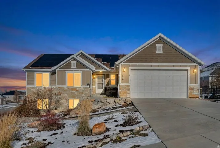 Craftsman-style house with stone siding, concrete driveway, roof mounted solar panels, and a garage