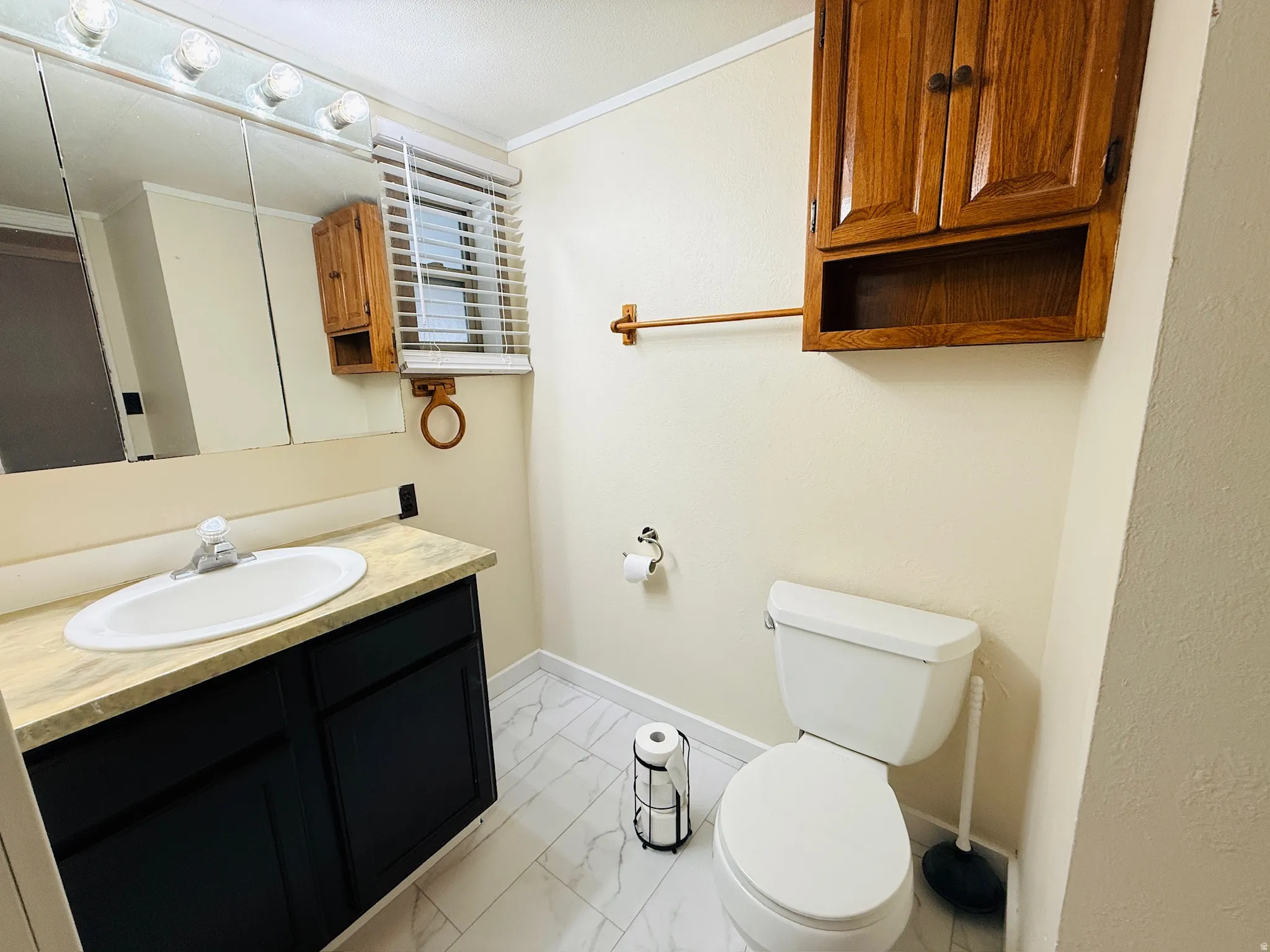 Half bath featuring ornamental molding, vanity, and light marble finish flooring