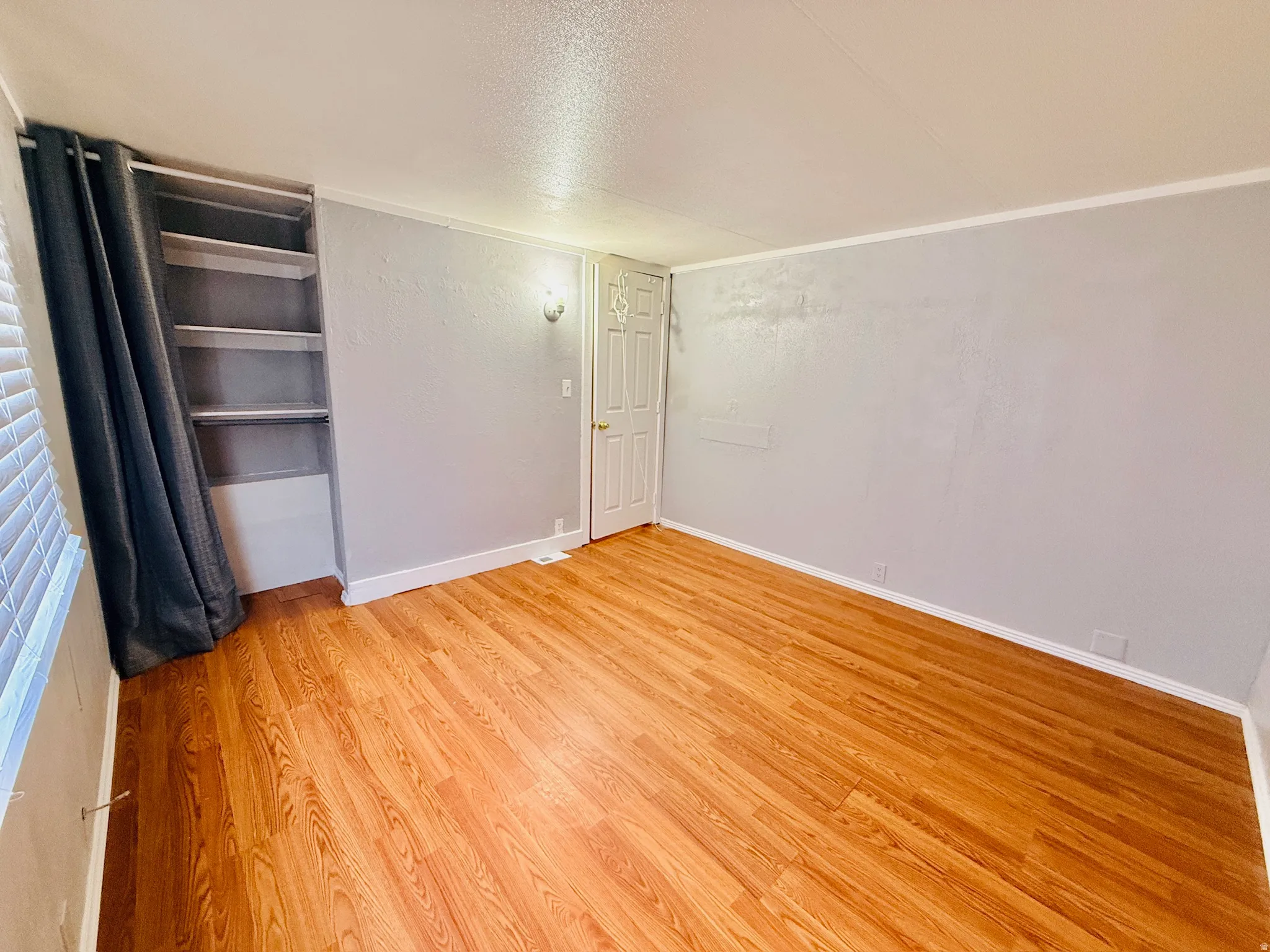 Unfurnished bedroom featuring a textured ceiling, light wood finished floors, and a closet