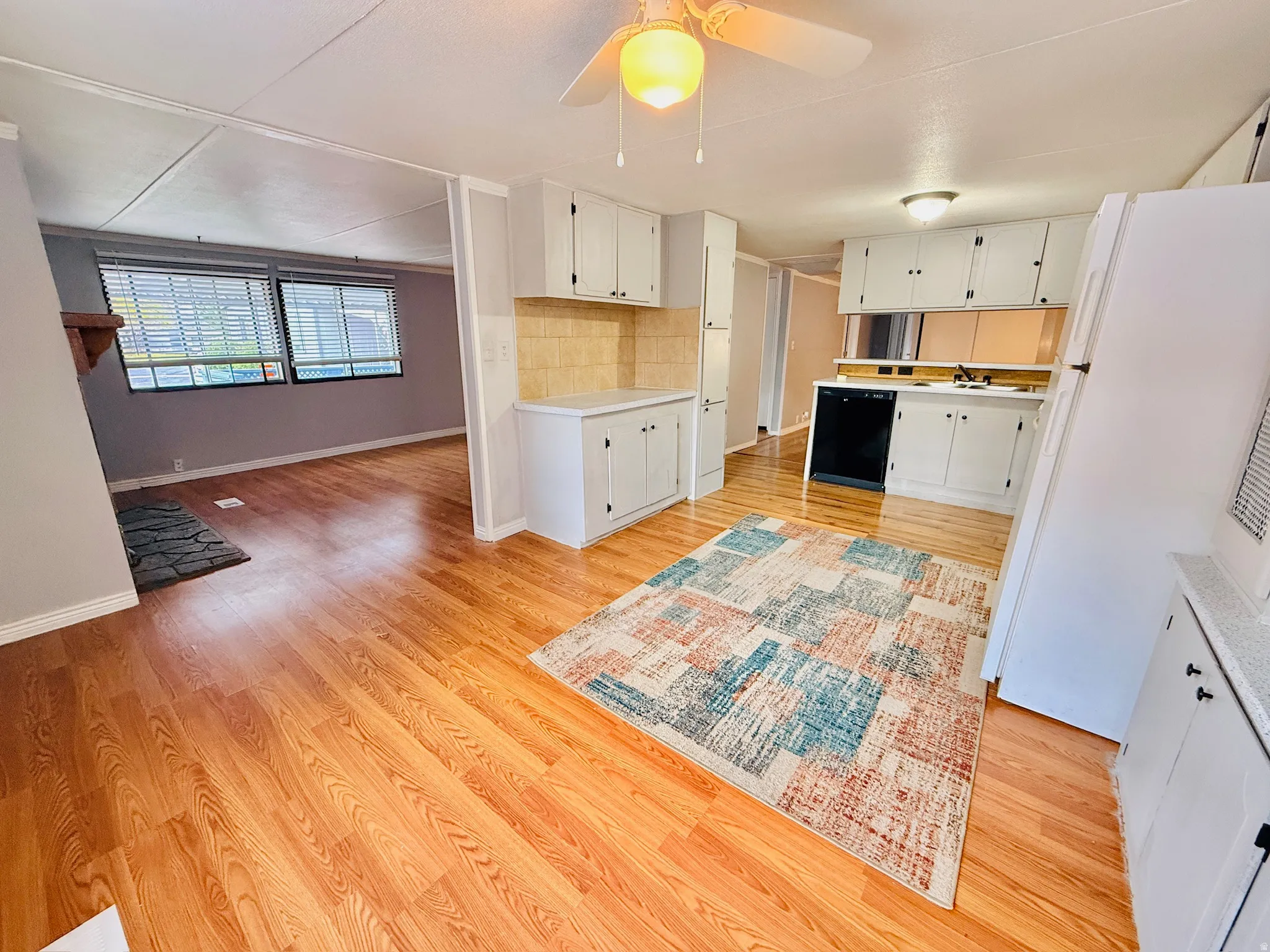 Kitchen featuring freestanding refrigerator, light wood-style floors, white cabinets, and light countertops