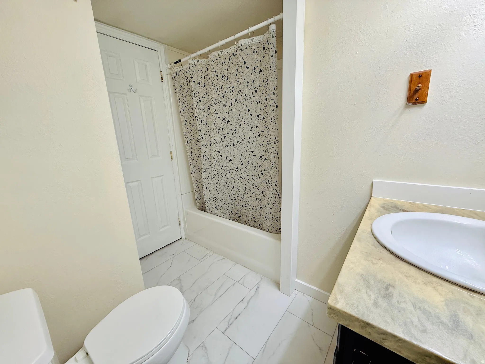 Bathroom with vanity, light marble finish floors, and shower / bath combo