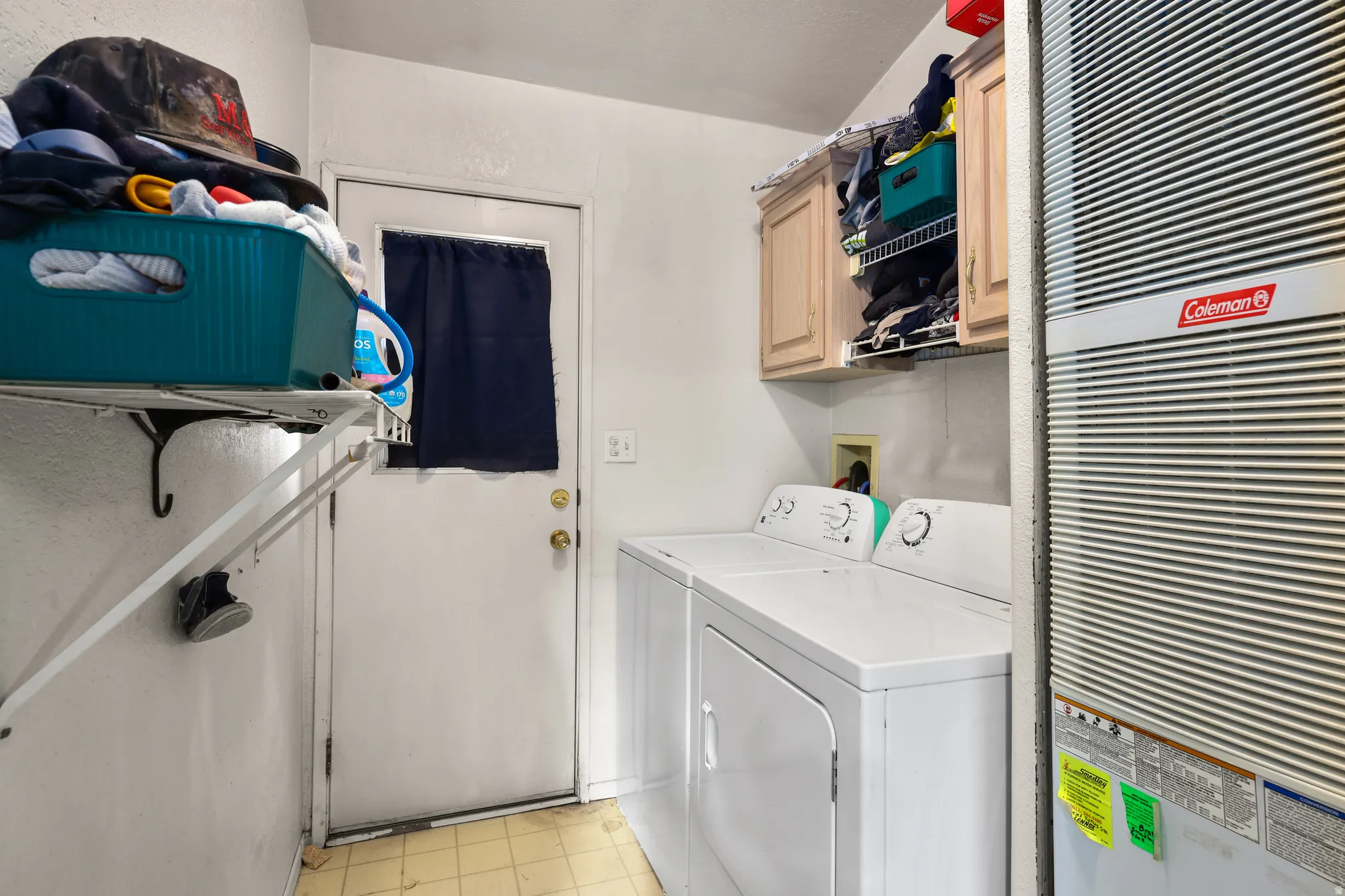 Laundry room with a heating unit, cabinet space, and washing machine and clothes dryer