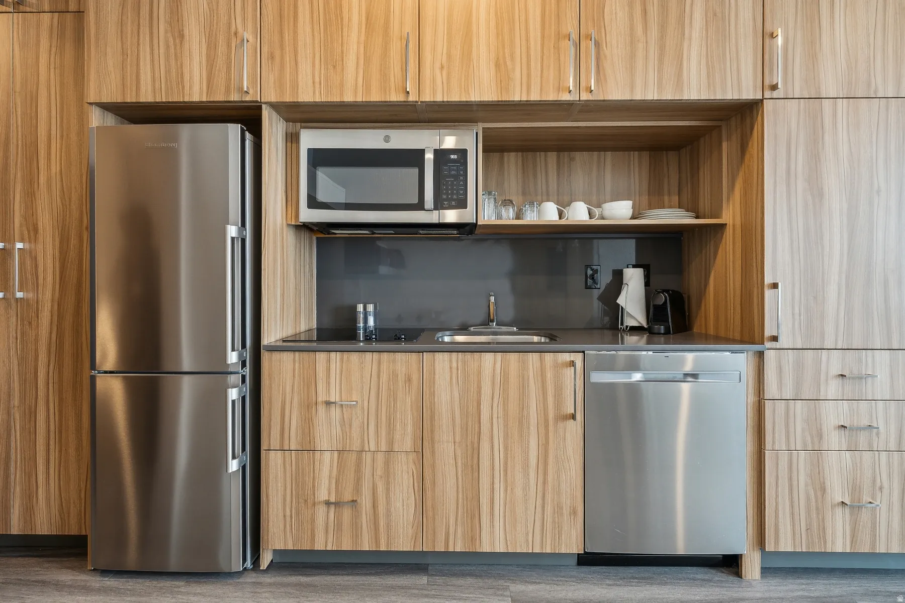 Kitchen featuring modern cabinets, open shelves, stainless steel appliances, and dark countertops