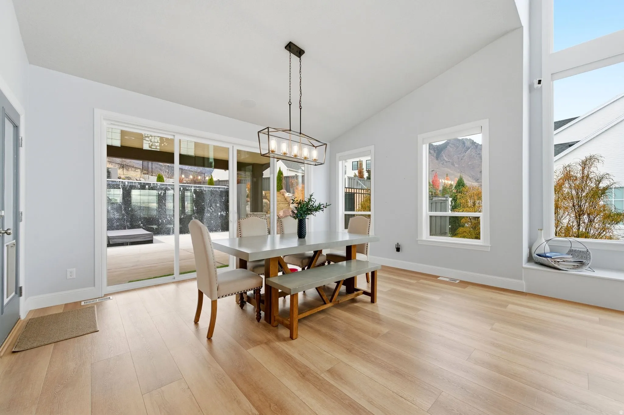 Dining room featuring vaulted ceiling, healthy amount of natural light, light wood-type flooring, and a chandelier