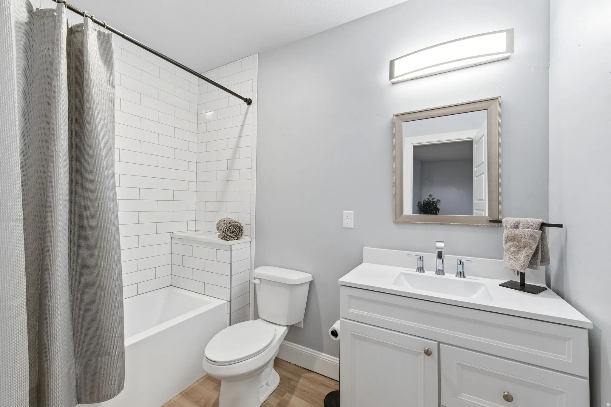 Full bath featuring shower / bathtub combination with curtain, vanity, and light wood-type flooring