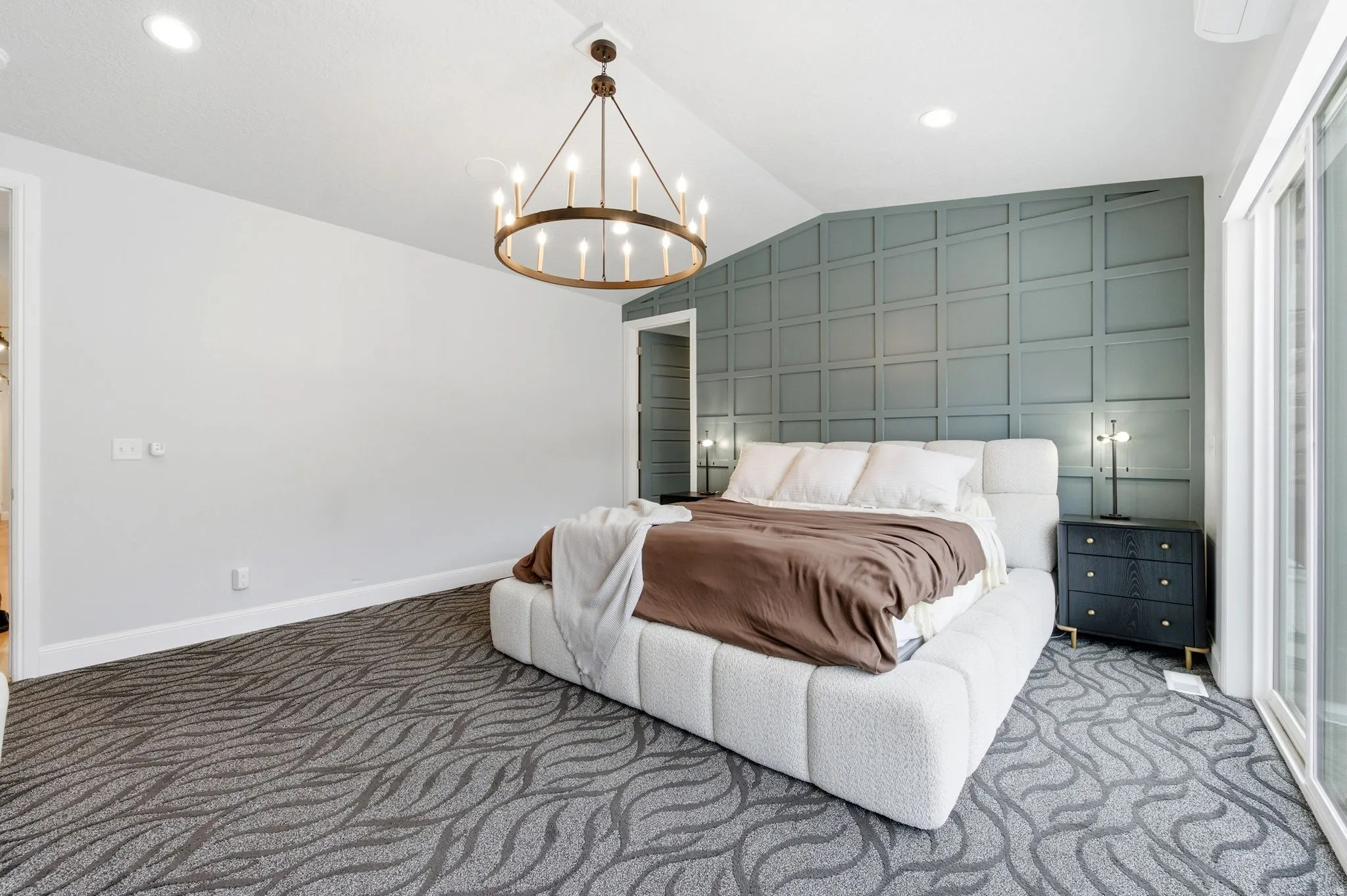 Carpeted bedroom featuring lofted ceiling, recessed lighting, a chandelier, and an accent wall
