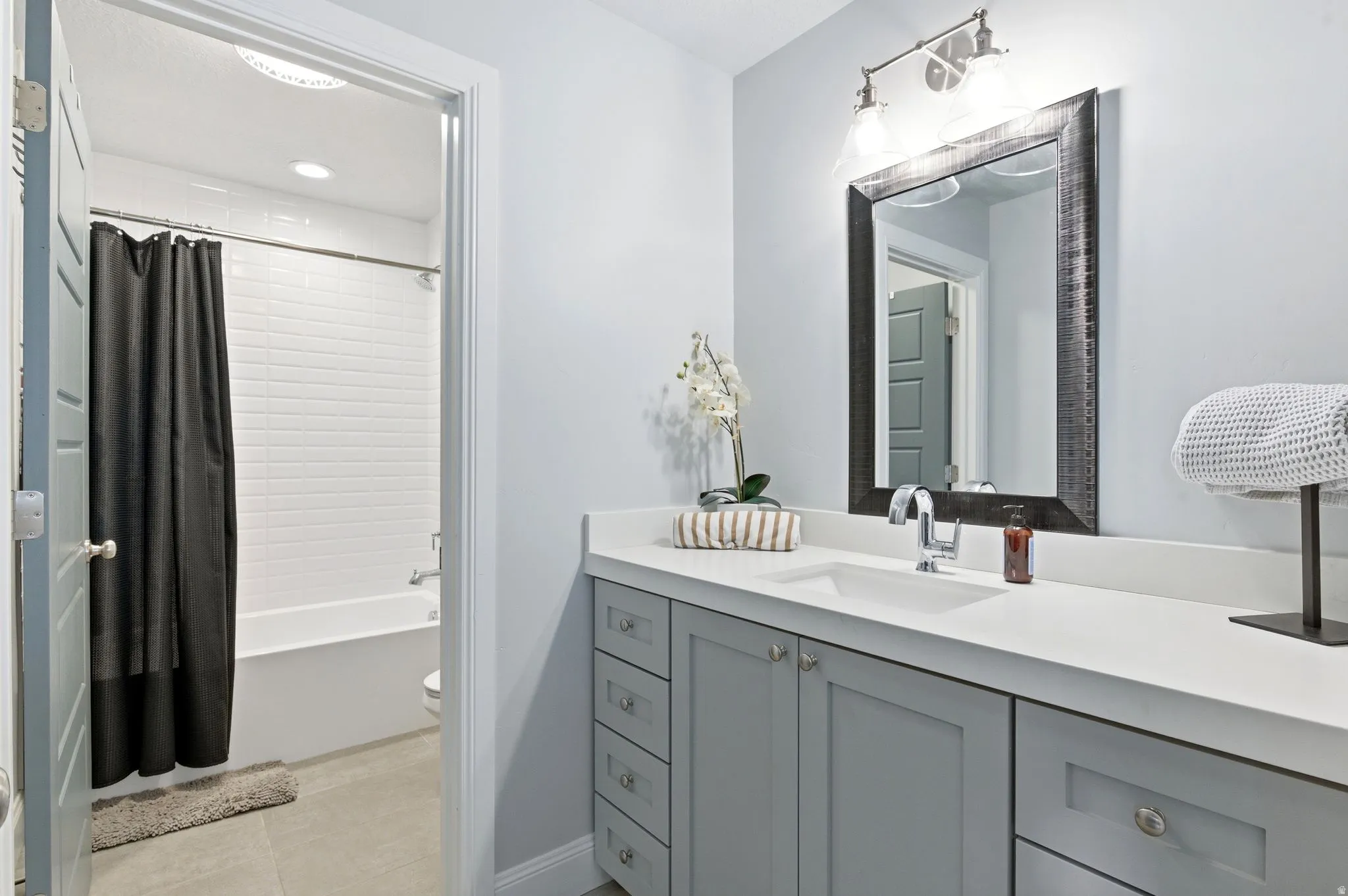Full bath with vanity, shower / bath combination with curtain, and light tile patterned flooring