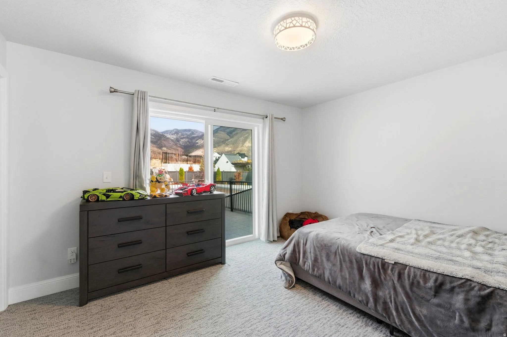Bedroom with light carpet, access to exterior, a mountain view, and a textured ceiling