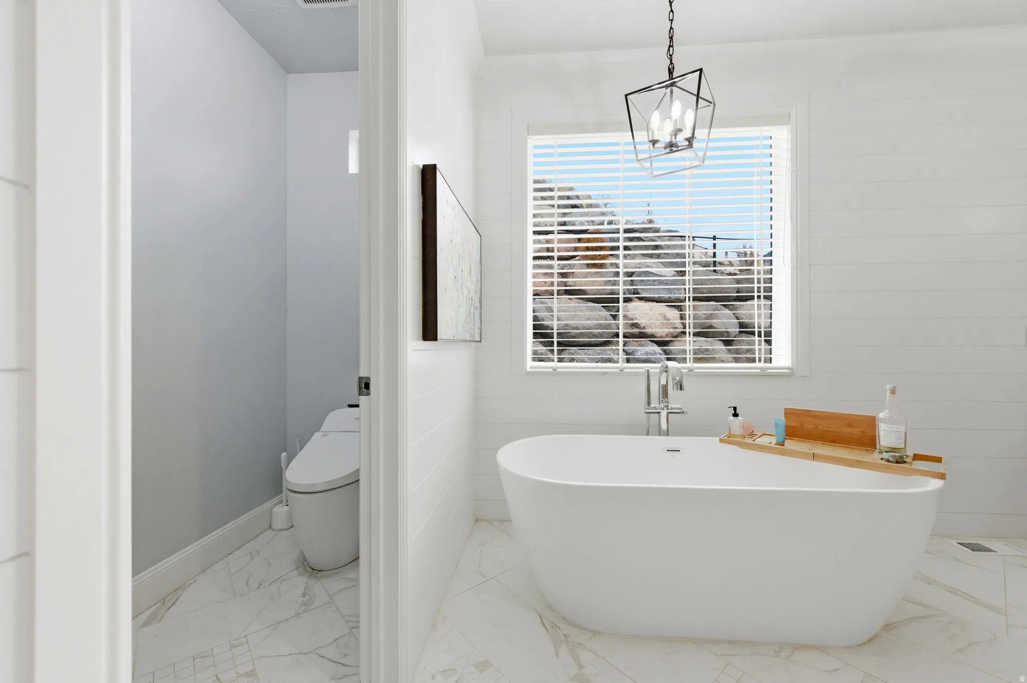 Bathroom featuring light marble finish flooring and a soaking tub