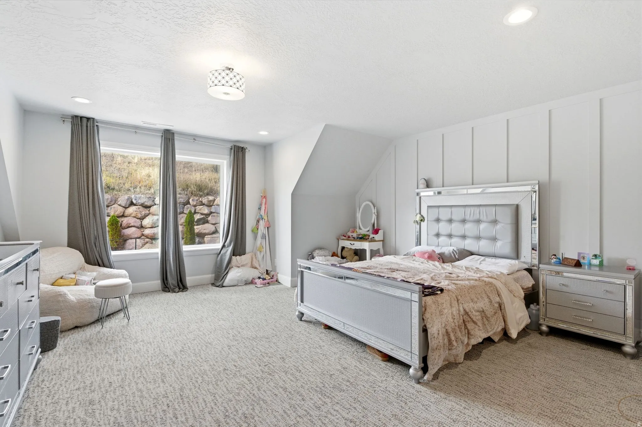 Bedroom with light carpet, lofted ceiling, a textured ceiling, and a decorative wall