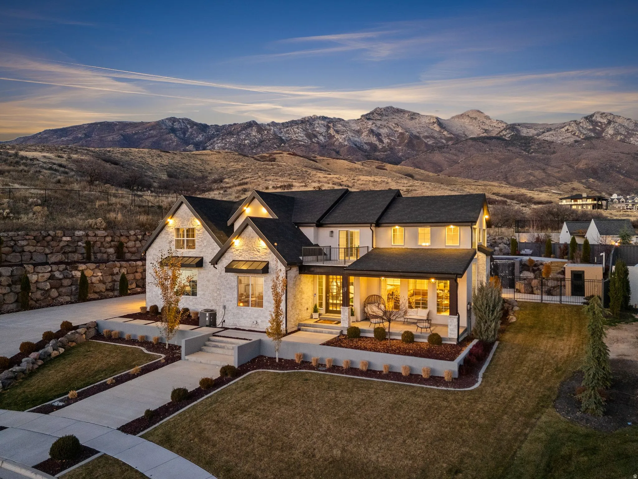 Back of property featuring stone siding, a mountain view, a lawn, and driveway