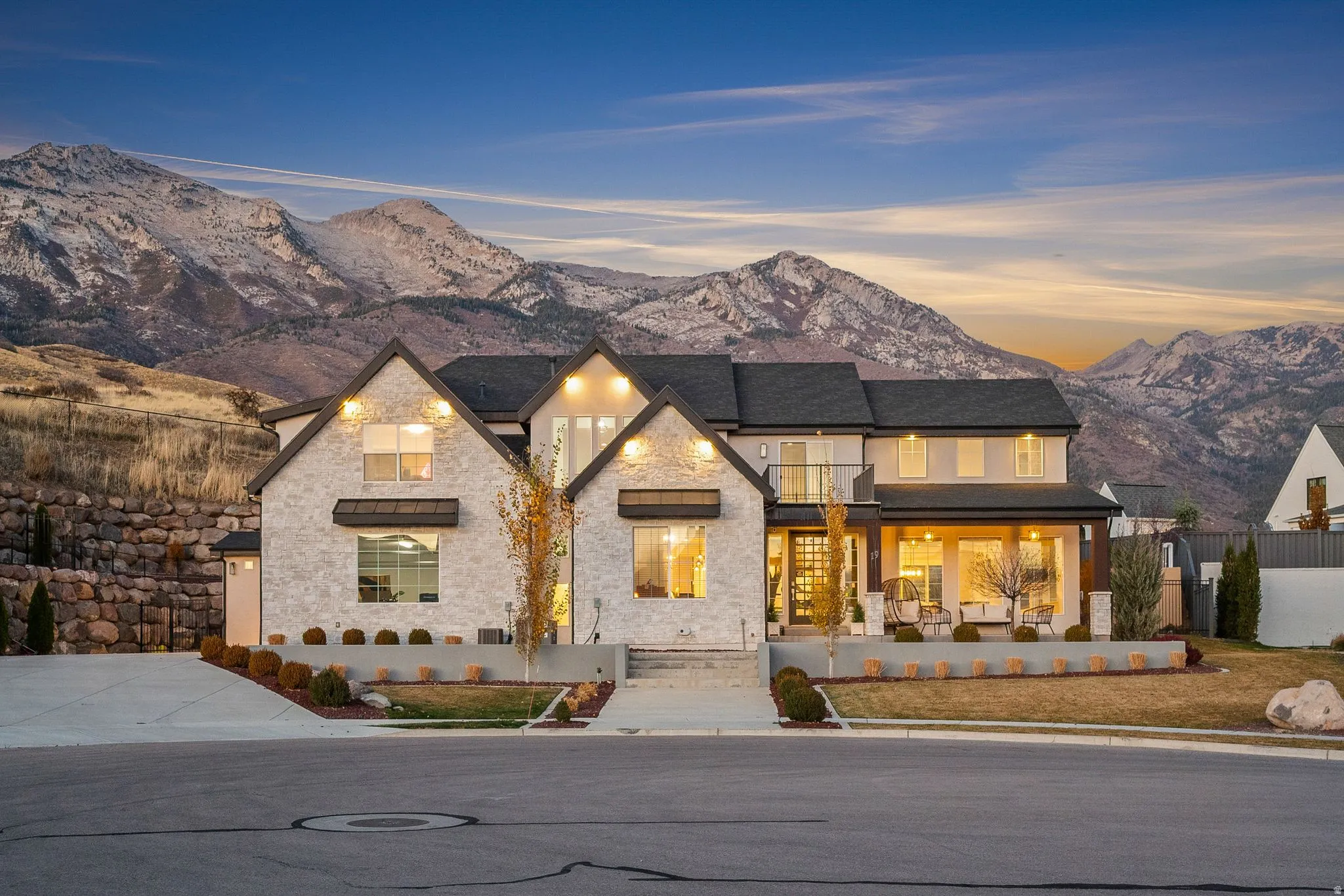 View of front of property with a mountain view, a balcony, stone siding, and a patio area