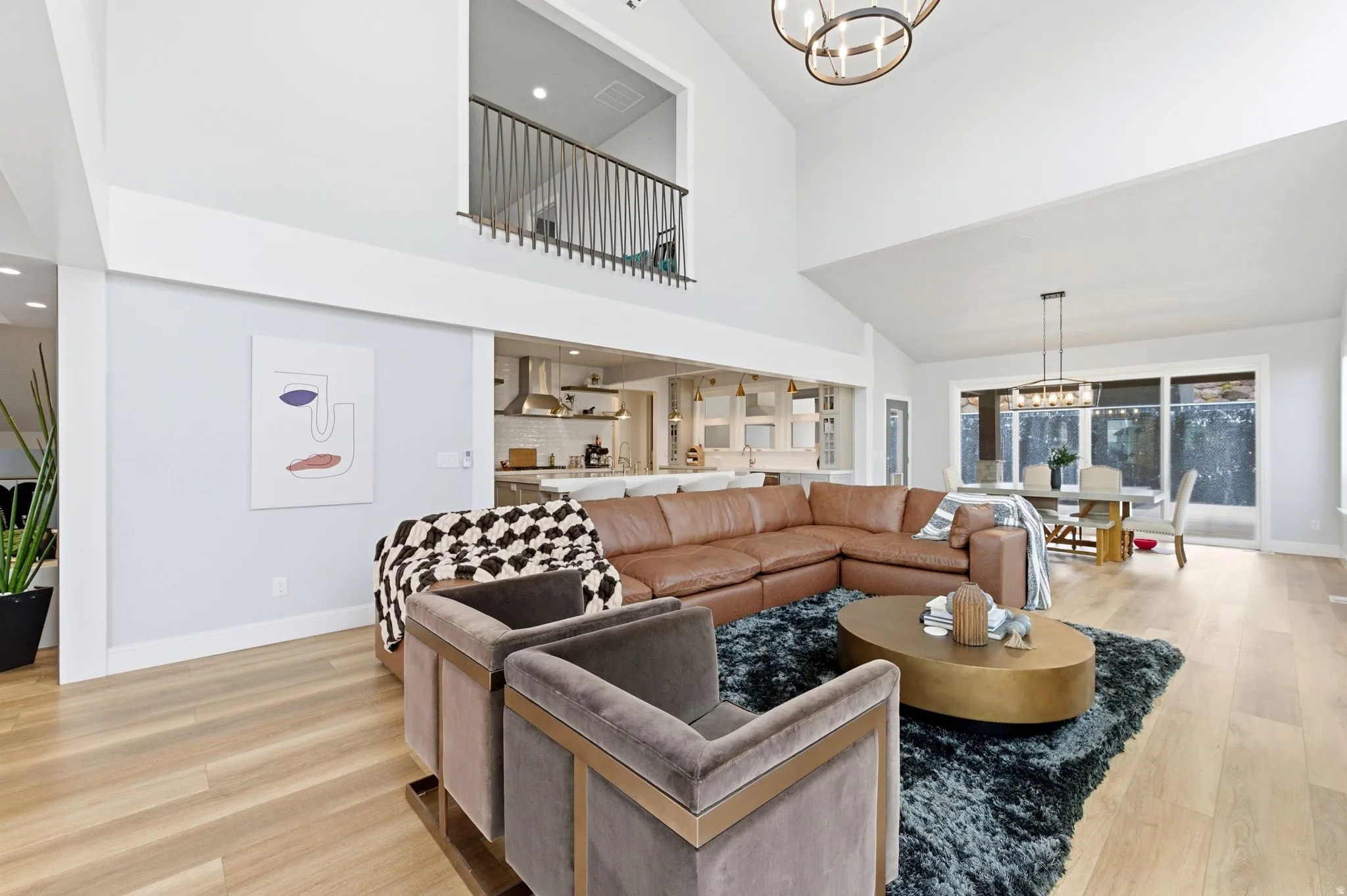 Living room featuring a chandelier, high vaulted ceiling, light wood-style floors, and recessed lighting