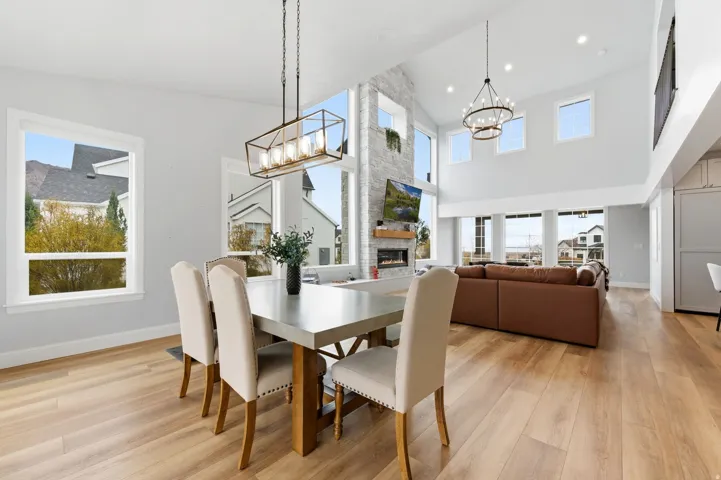 Dining area featuring a stone fireplace, light wood-style floors, and a chandelier