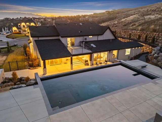 Back of property at dusk featuring a patio, a fenced backyard, and roof with shingles