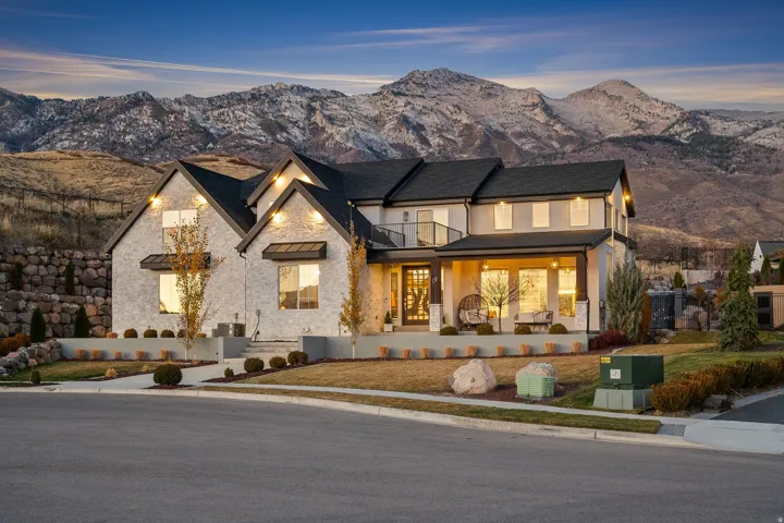 View of front of house featuring stone siding, a mountain view, a standing seam roof, a front yard, and stucco siding